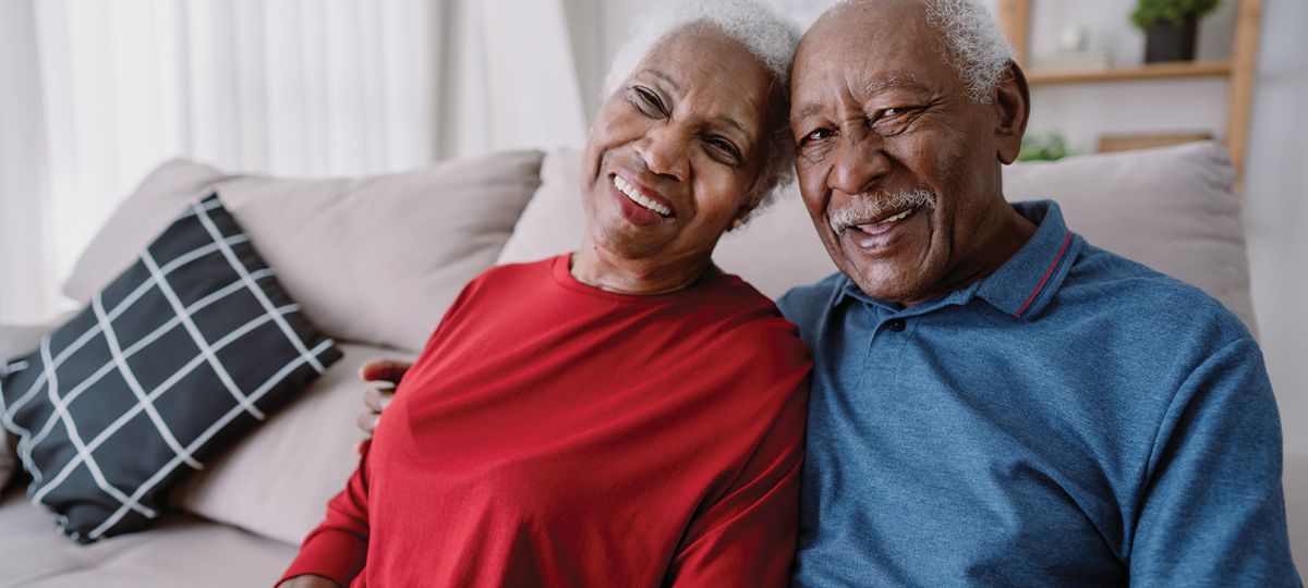 Smiling older Black couple sitting together in a cozy living room.